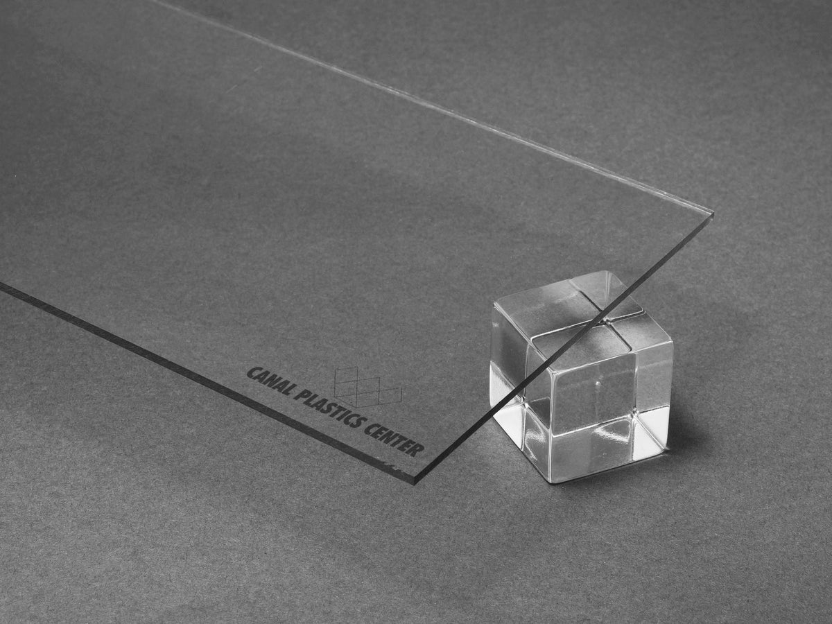 Clear polycarbonate sheet resting on a transparent acrylic cube with a soft off-white background and subtle 3D shadow, showcasing the material’s clarity and smooth edges